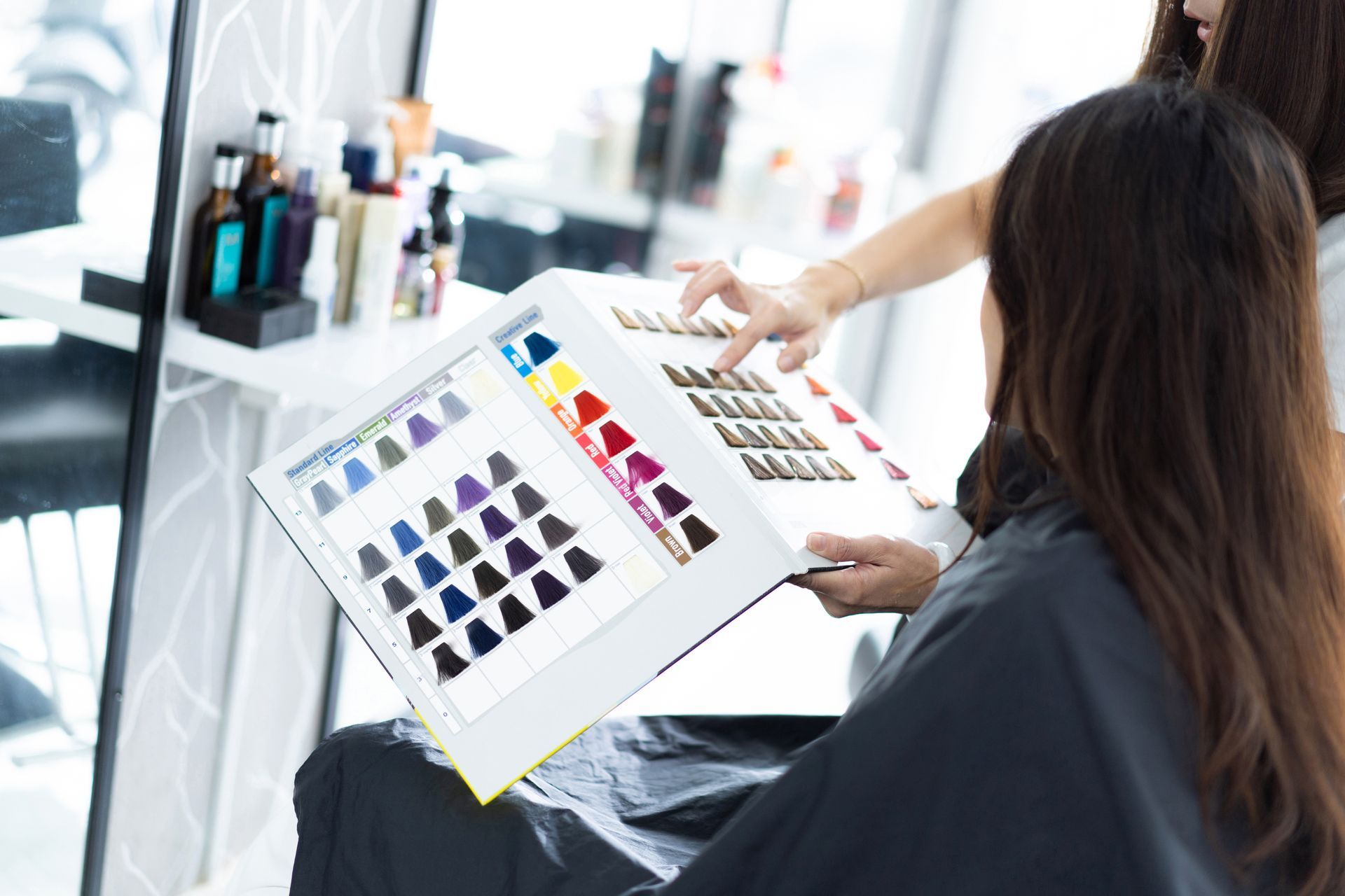 Person reviewing a color swatch book in a salon chair