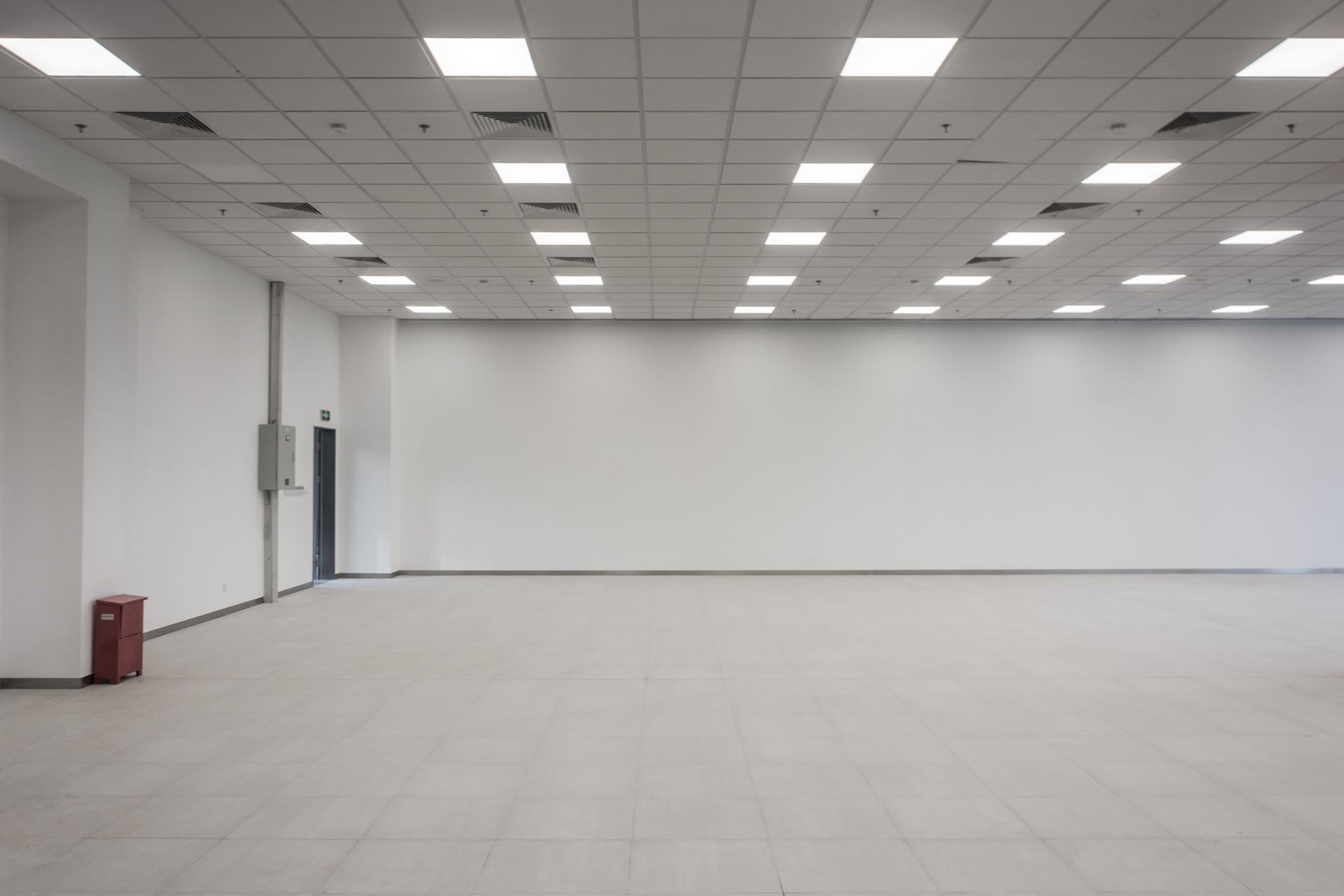 Empty bright room with white walls, tiled floor, and ceiling lights