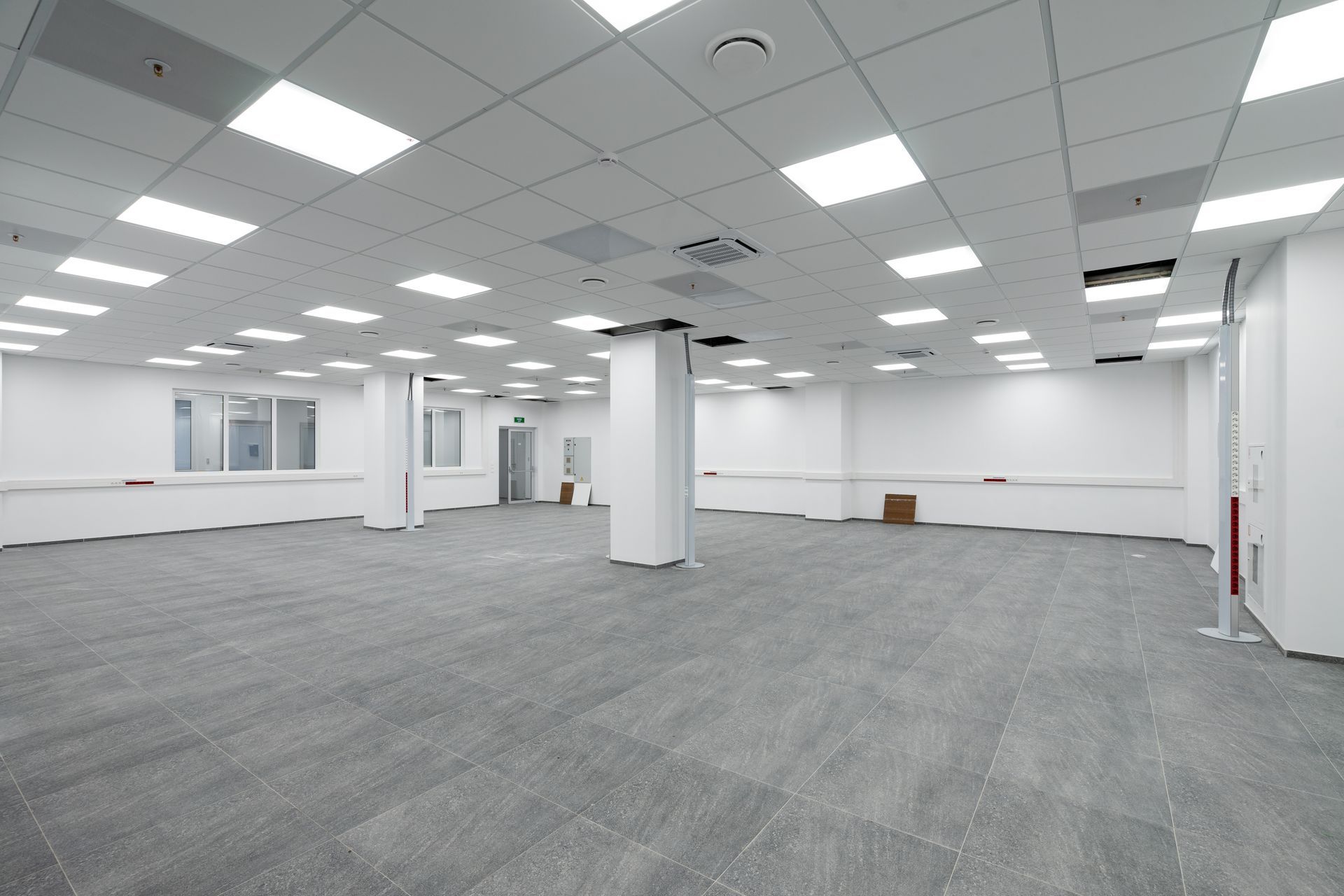 Empty office space with gray carpet, white walls, and bright fluorescent ceiling lights