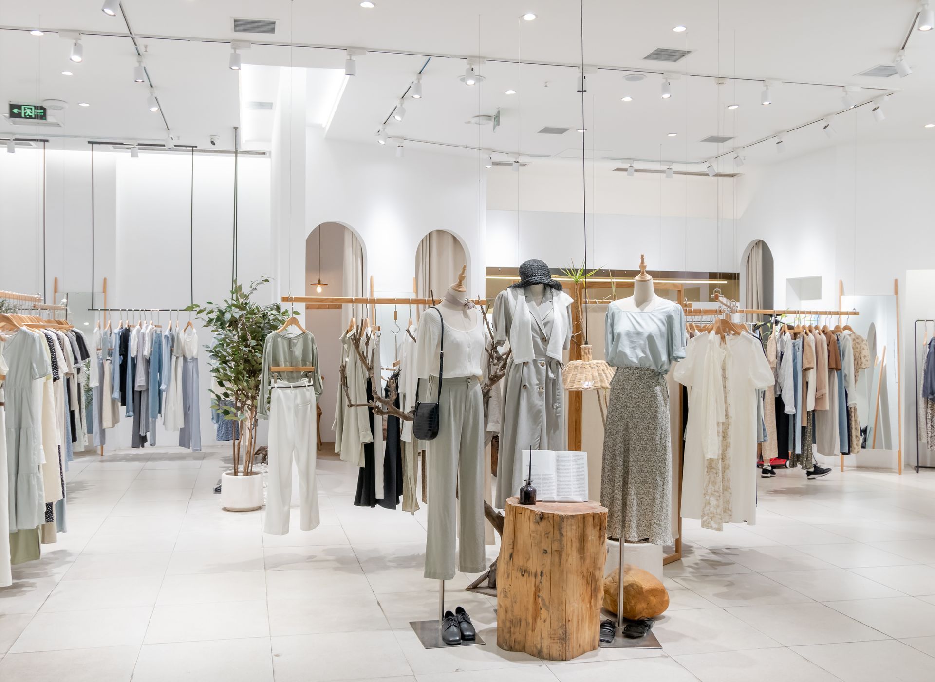 Bright minimalist clothing boutique with racks of neutral-toned garments and mannequins on display