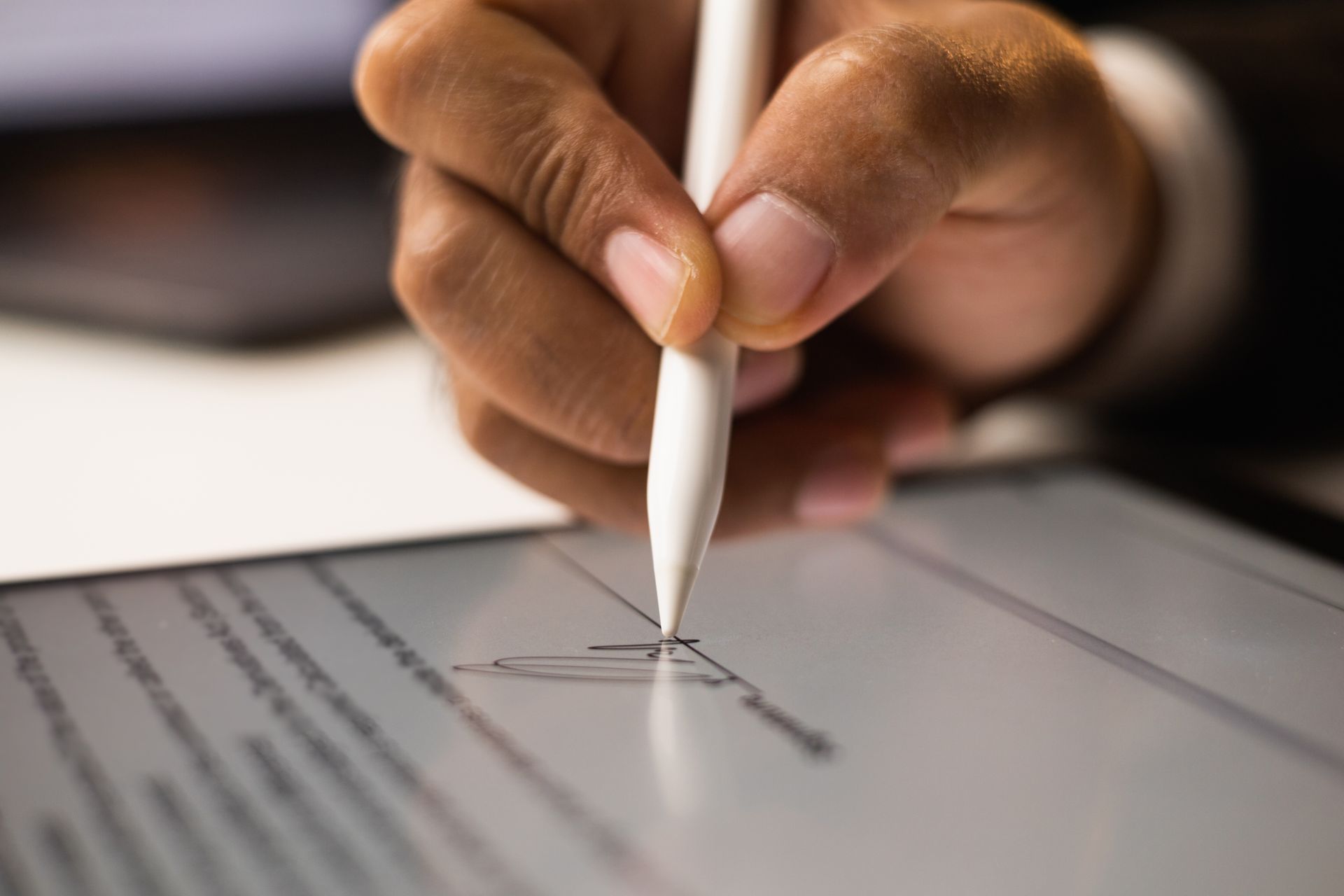 Hand signing a document on a tablet with a white stylus