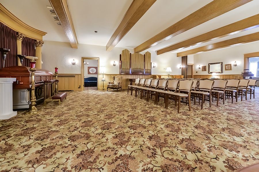 John F. Fluehr & Sons, Inc chapel with rows of chairs, an organ, and a floral patterned carpet.