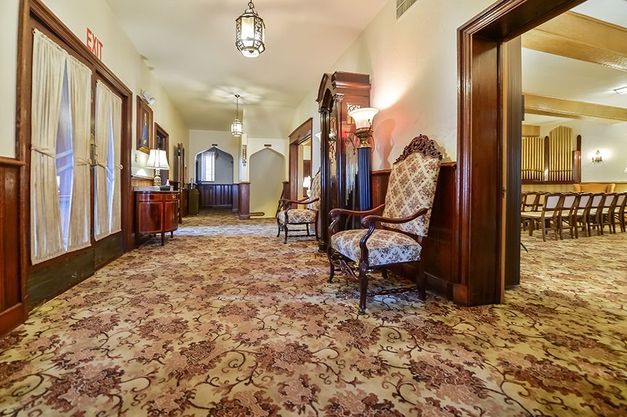 John F. Fluehr & Sons, Inc Hallway with patterned carpet, wood paneling, and a patterned armchair.