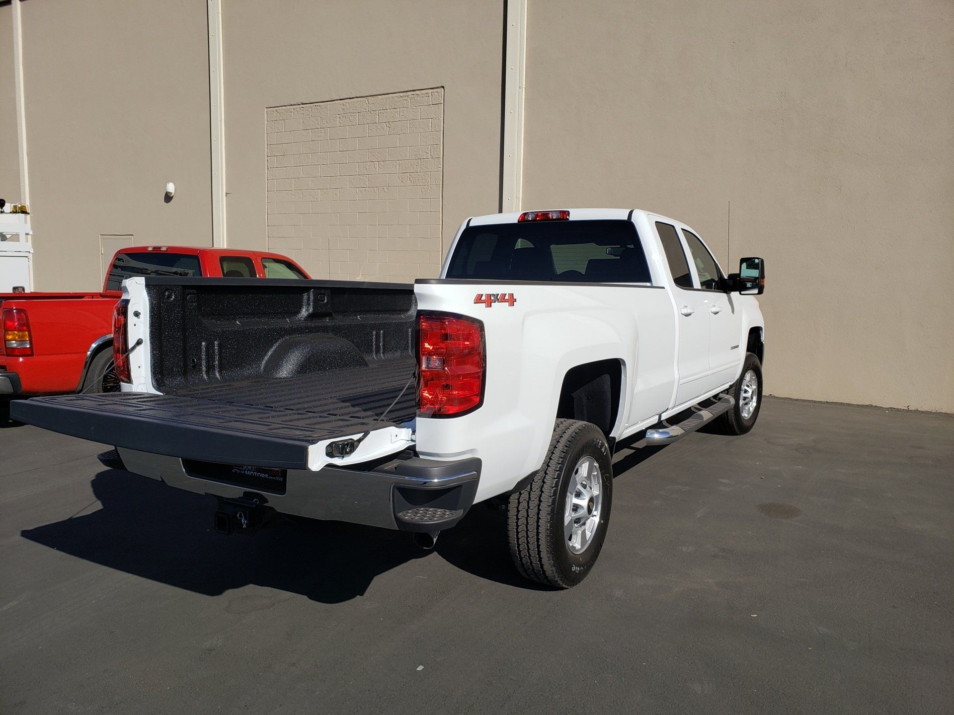 A white truck with a crane on top of it is parked in a parking lot.