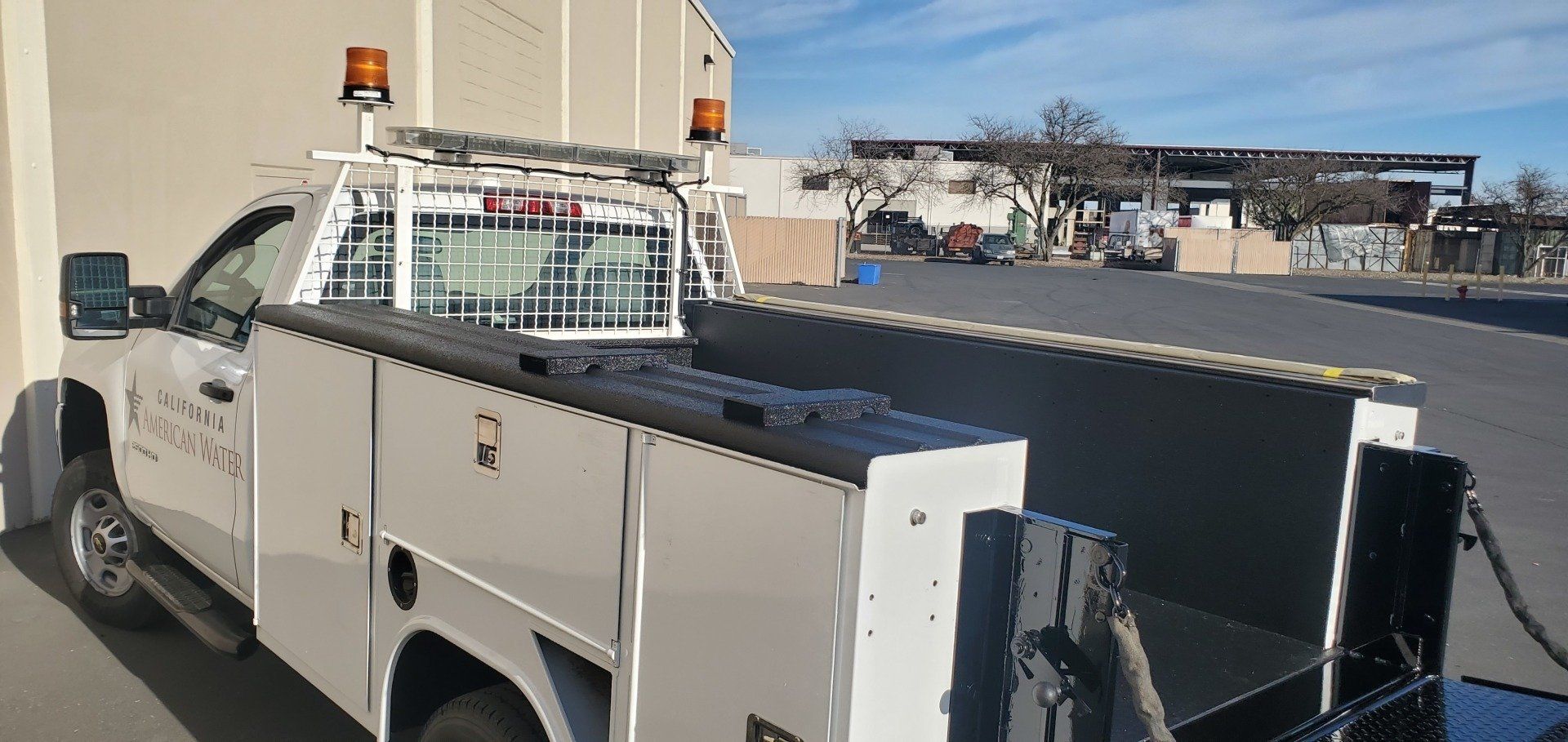 A white truck with a crane on top of it is parked in a parking lot.