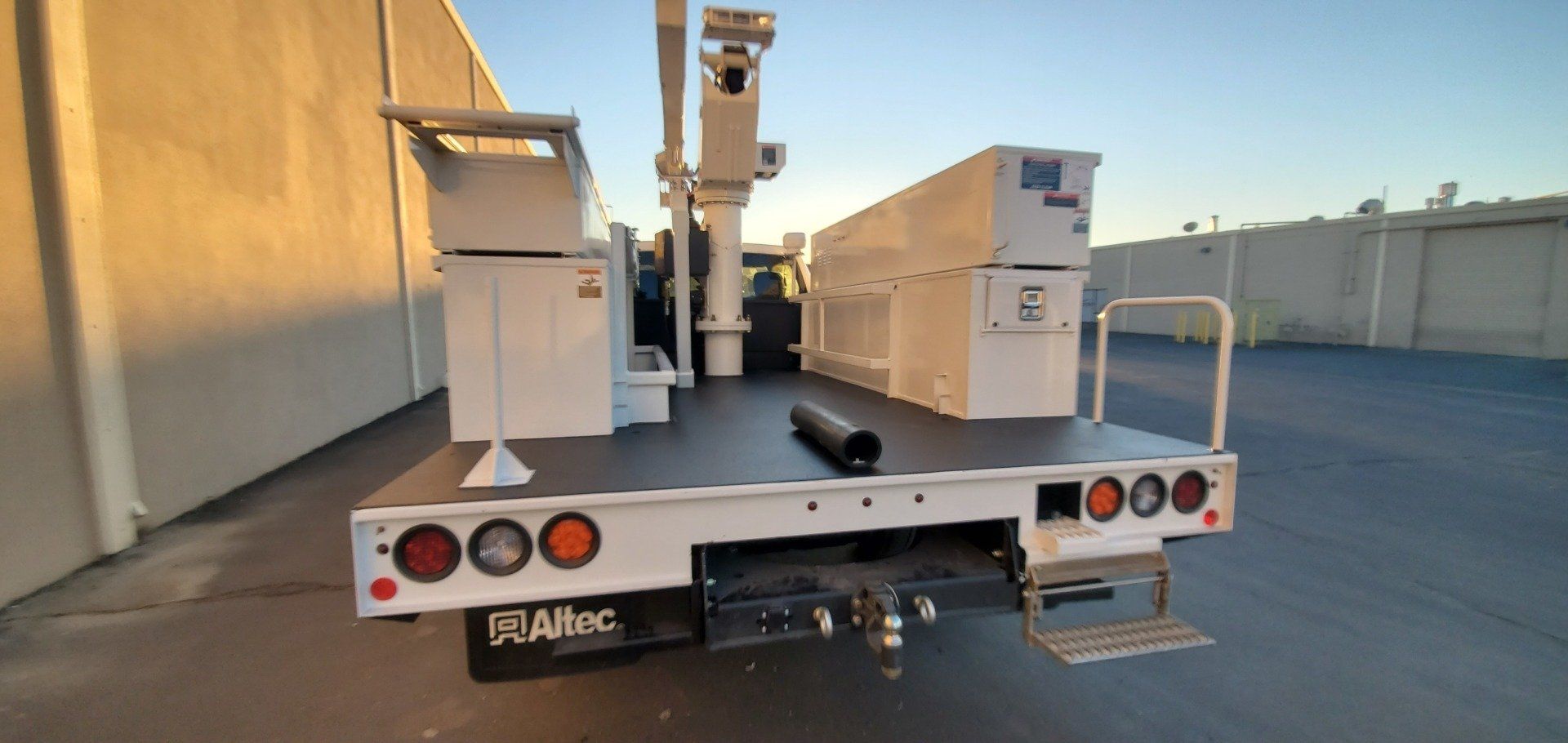 A white truck with a crane on the back is parked in a parking lot.
