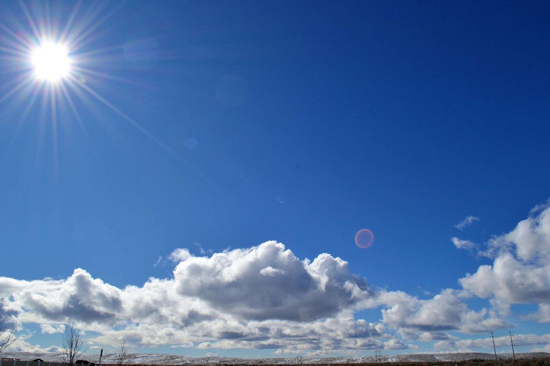 The sun is shining brightly through the clouds in the blue sky.