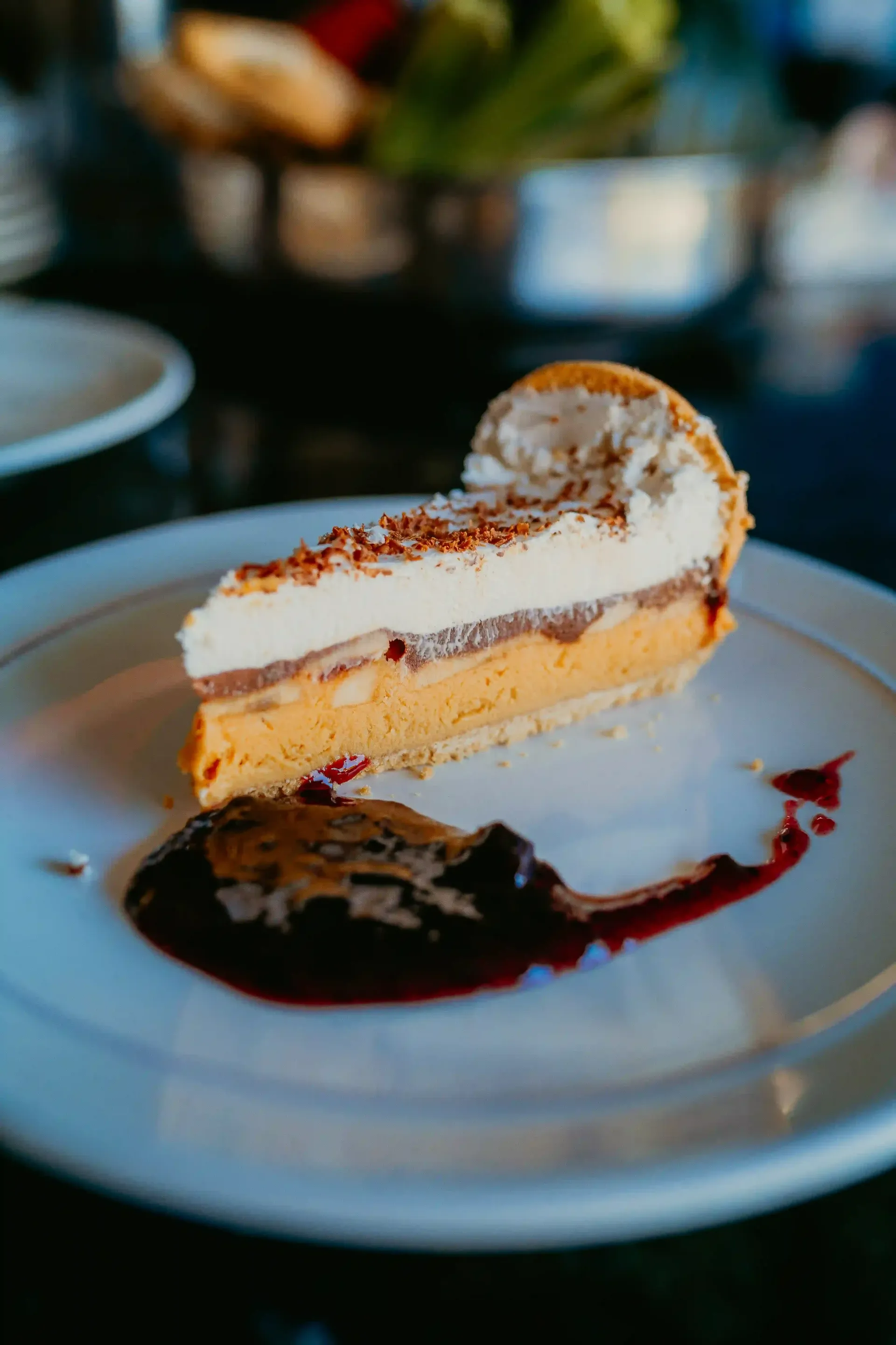 Uma fatia de cheesecake com molho em um prato branco.-Pousada-Recanto-do-Chef