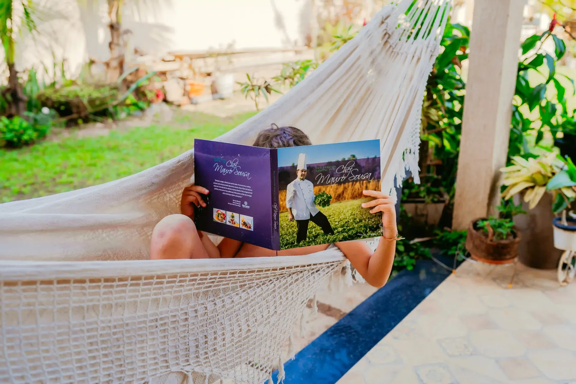 Uma pessoa está deitada em uma rede lendo um livro.-Pousada-Recanto-do-Chef