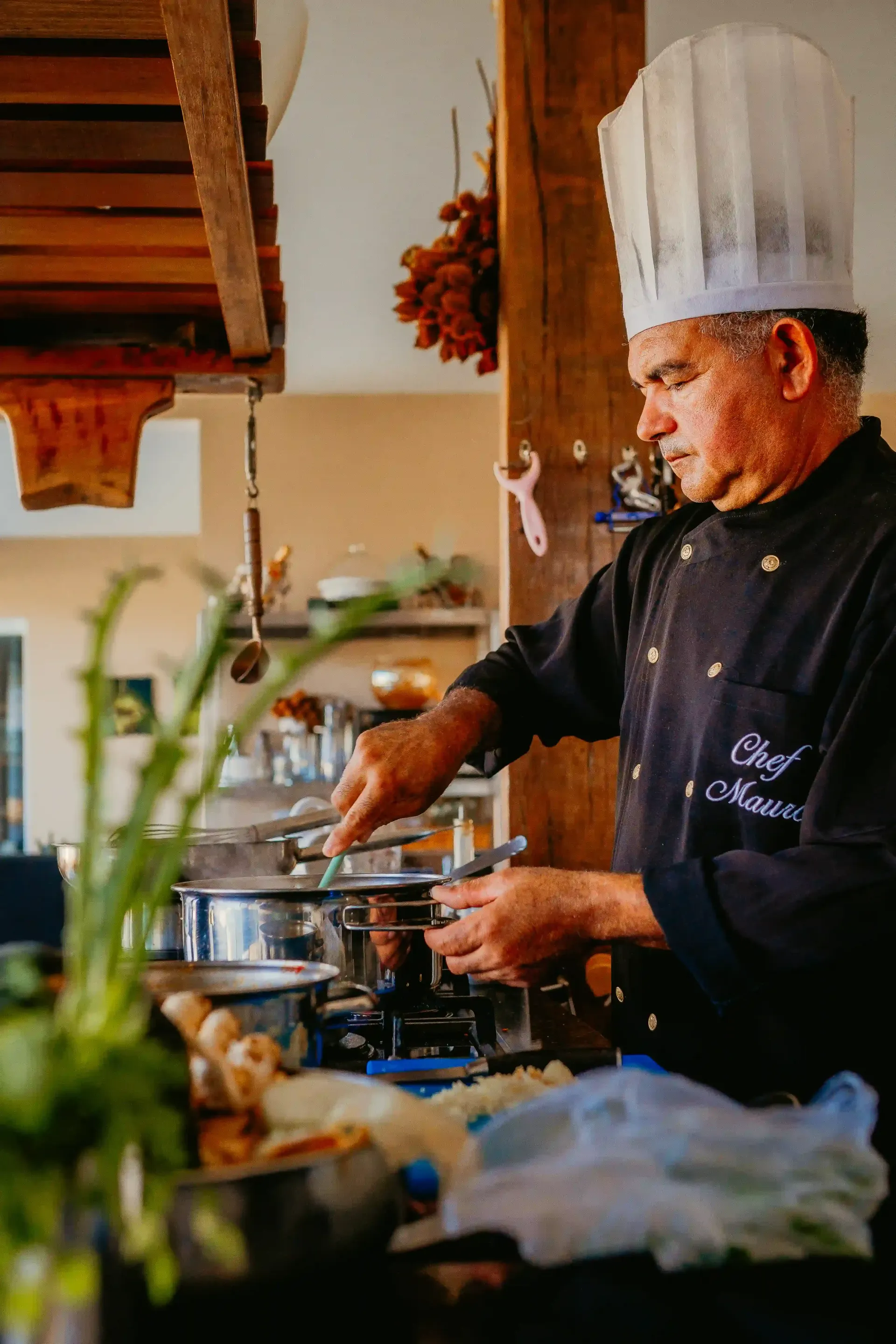 Um chef está preparando comida em uma cozinha.-Pousada-Recanto-do-Chef