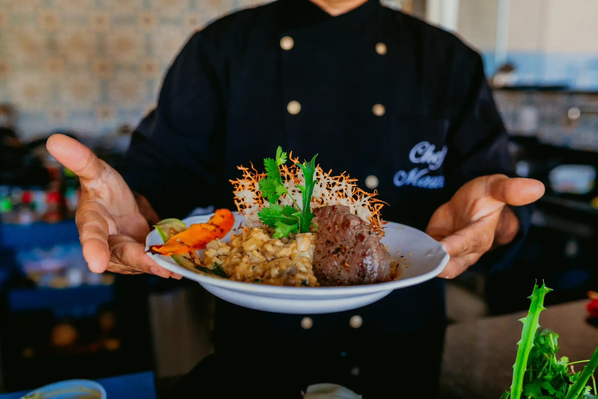 Um chef está segurando um prato de comida em suas mãos.-Pousada-Recanto-do-Chef