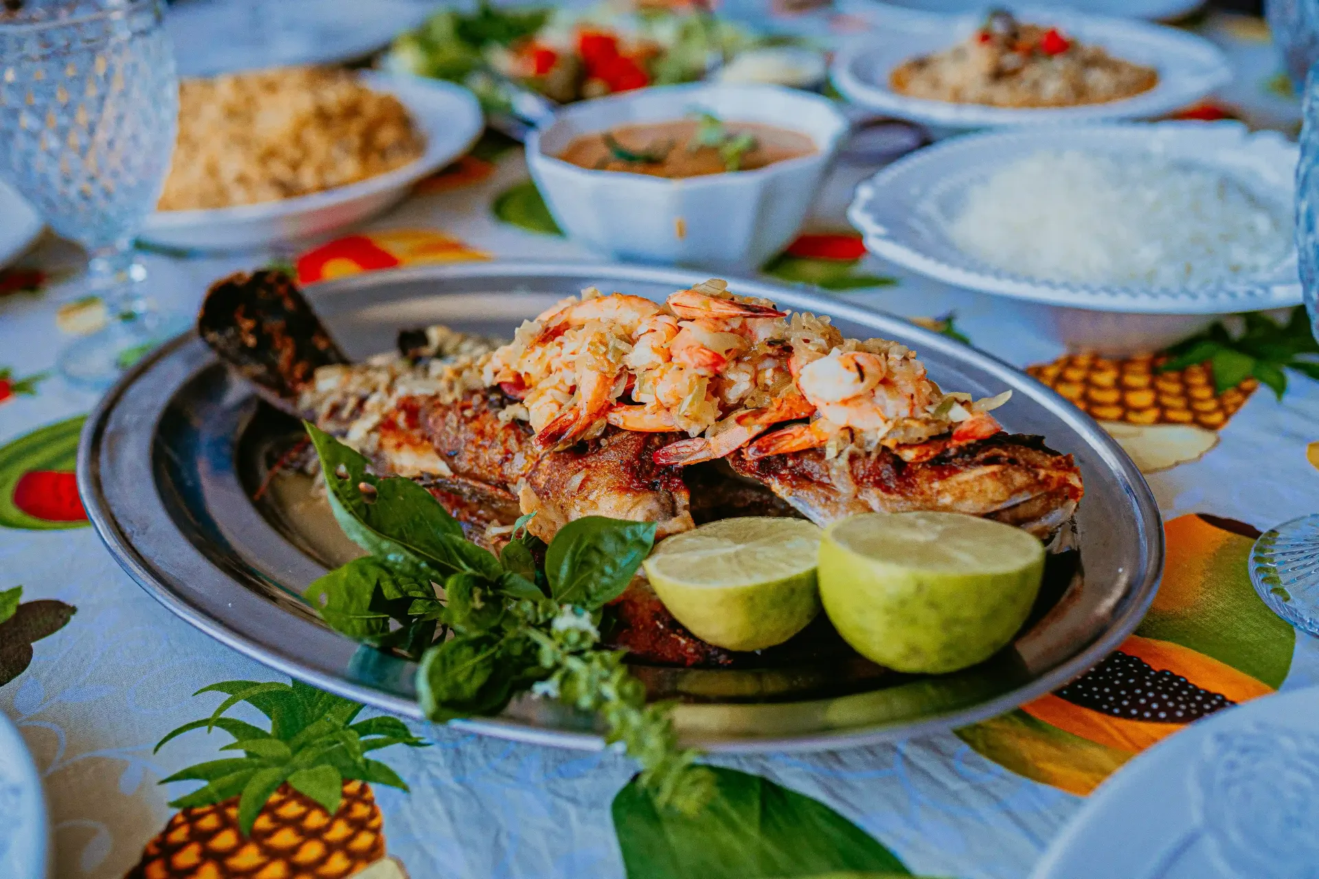 Um prato de peixe com camarão e limões sobre uma mesa.-Pousada-Recanto-do-Chef