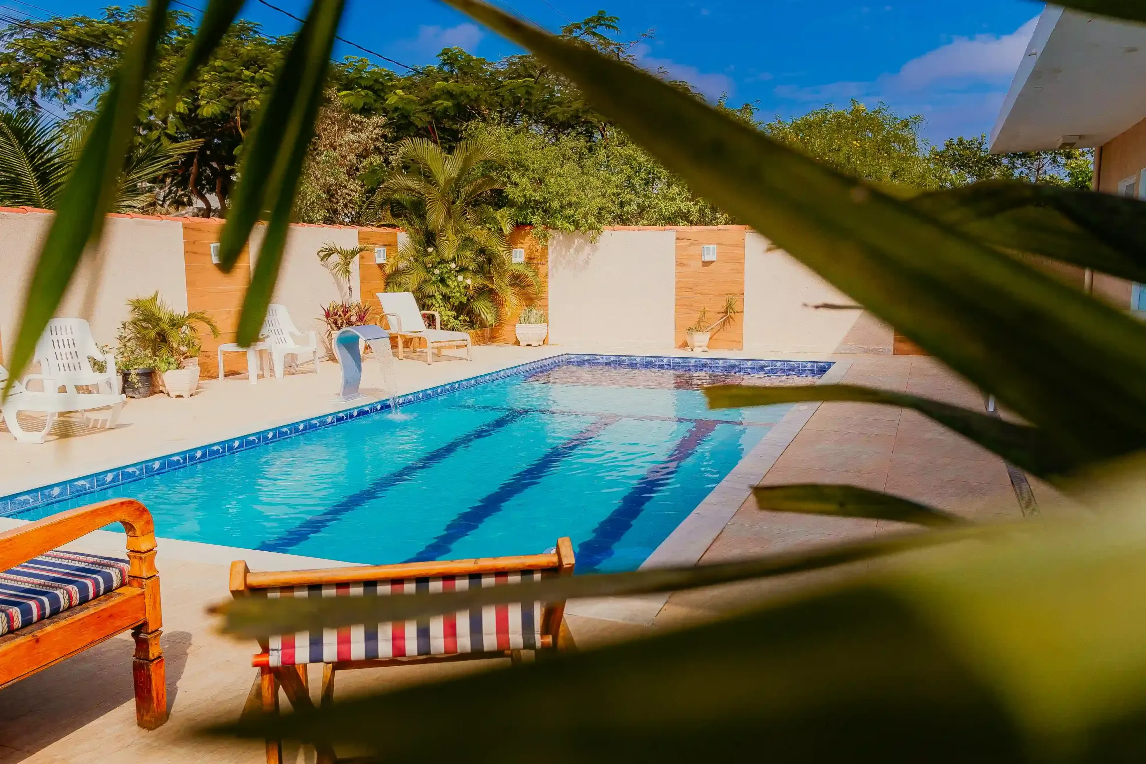 Uma piscina com um banco e cadeiras na frente dela.-Pousada-Recanto-do-Chef