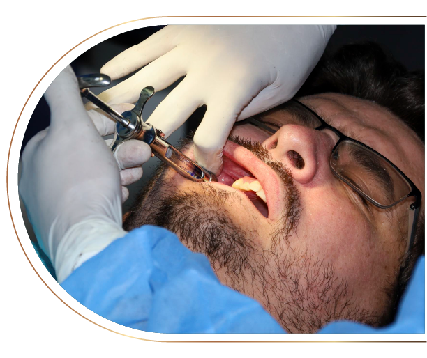 A man with glasses is getting an injection from a dentist