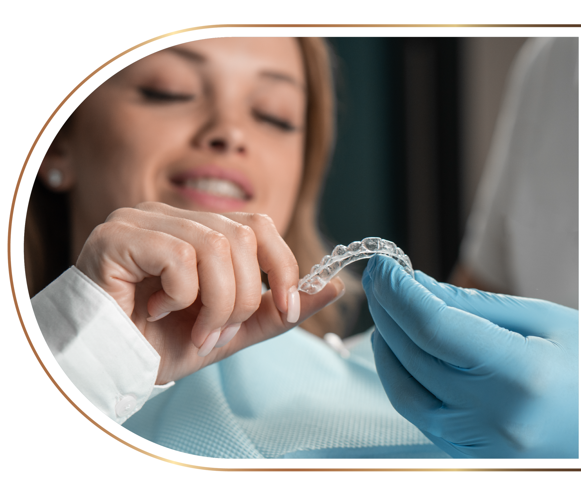 A woman is sitting in a dental chair holding a clear brace.