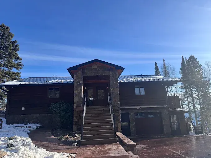 Snow-covered house with central staircase under a blue sky