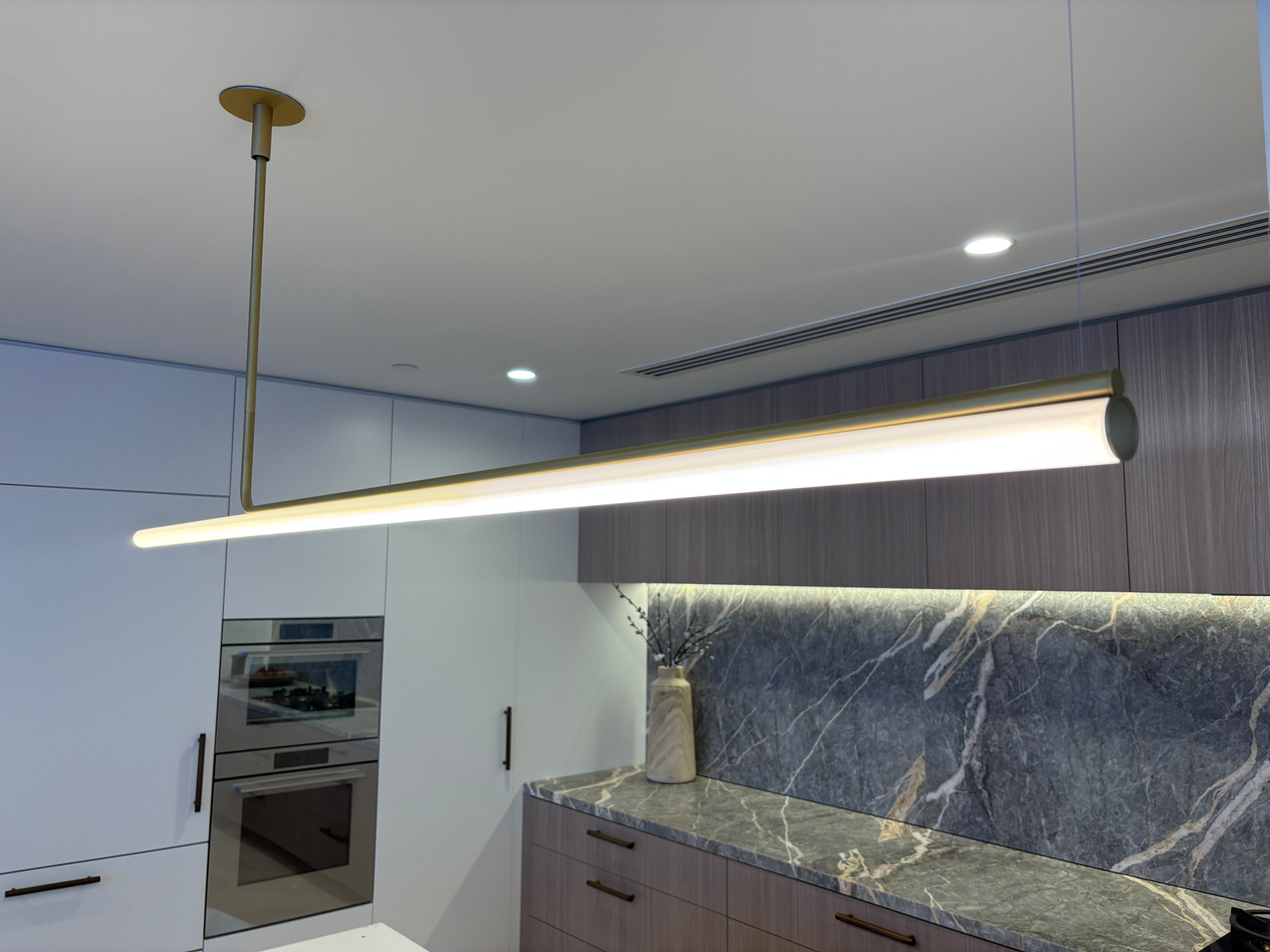 A kitchen with a long light hanging from the ceiling