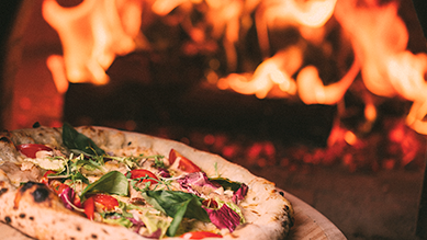A pizza is being cooked in a wood fired oven.