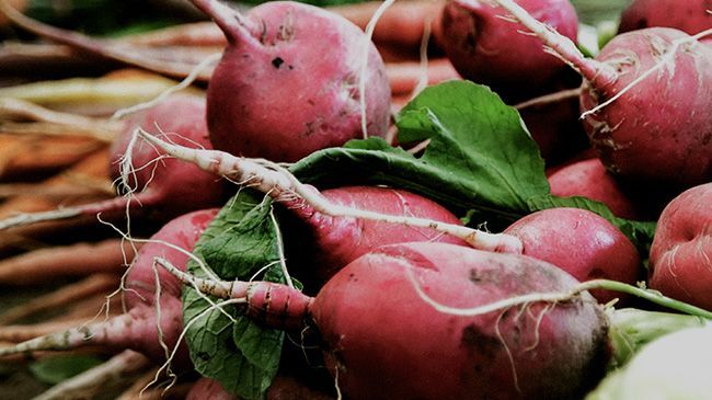 A bunch of radishes are sitting on top of each other on a table.