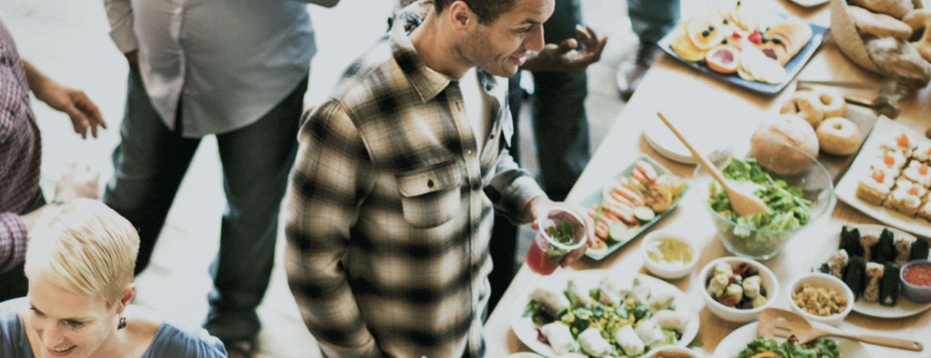Header Catering man holding drink over spread of food