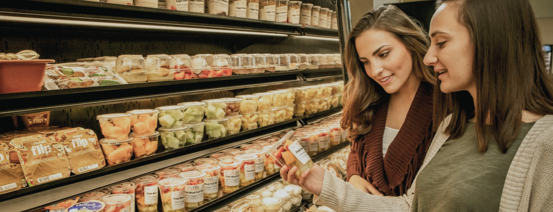 Two people looking at the nutrition facts on a pack of fruit