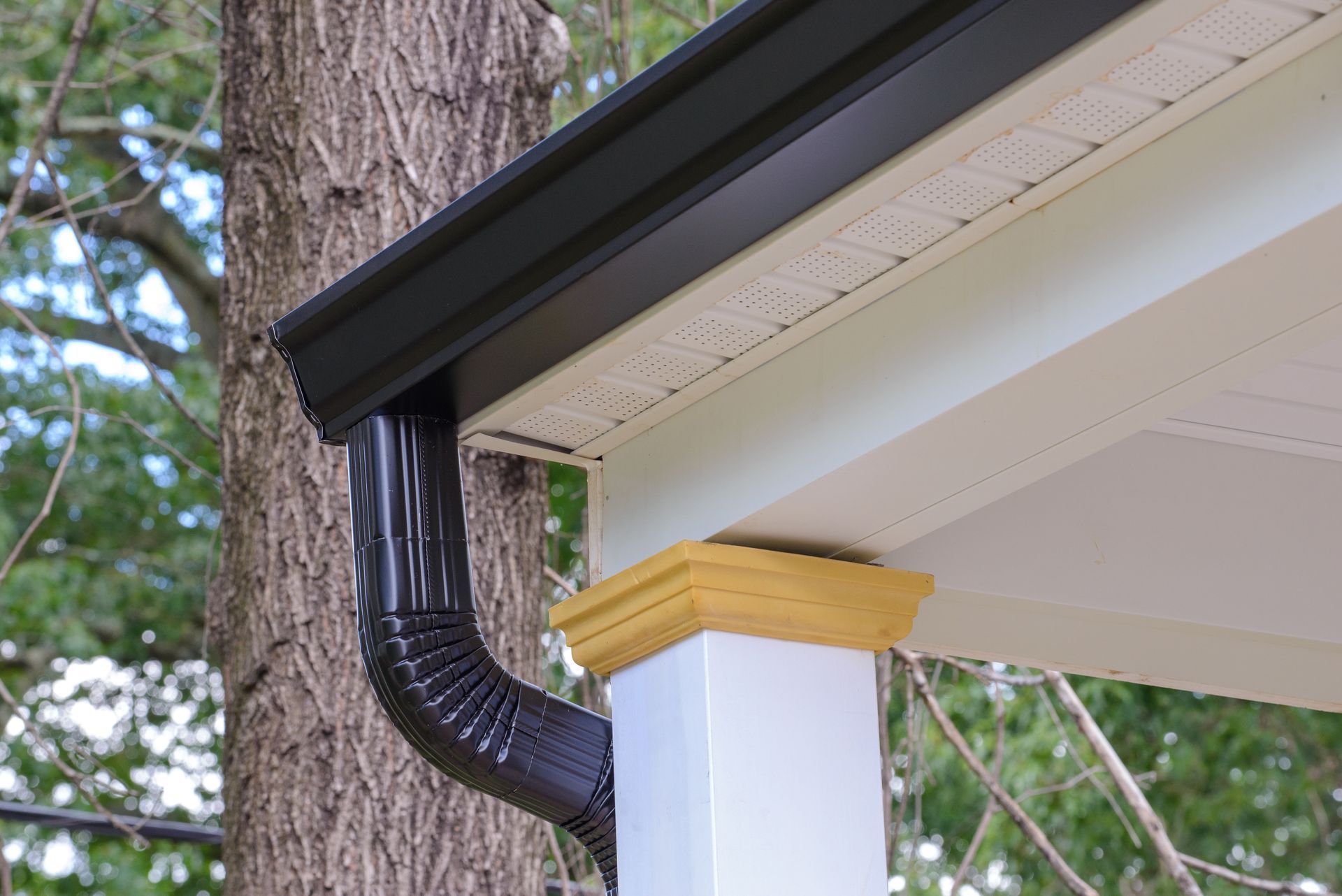 A black gutter is attached to the roof of a porch.