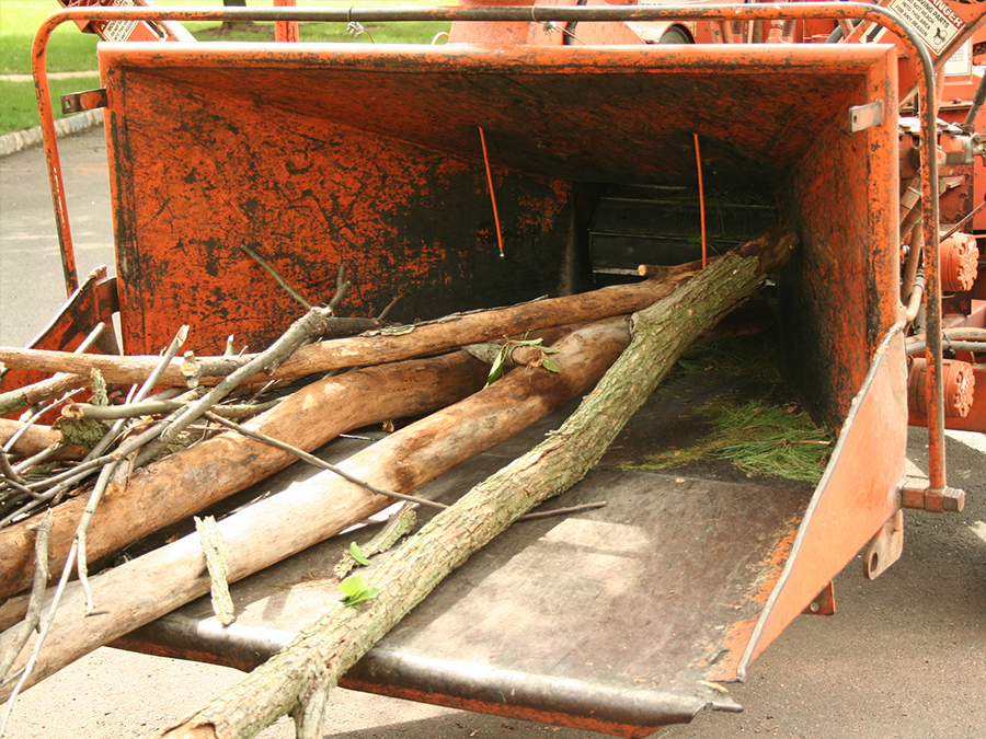 A wood chipper is filled with branches and grass