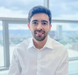 Una persona con barba, que viste una camisa blanca abotonada con el logotipo de FEBECOL