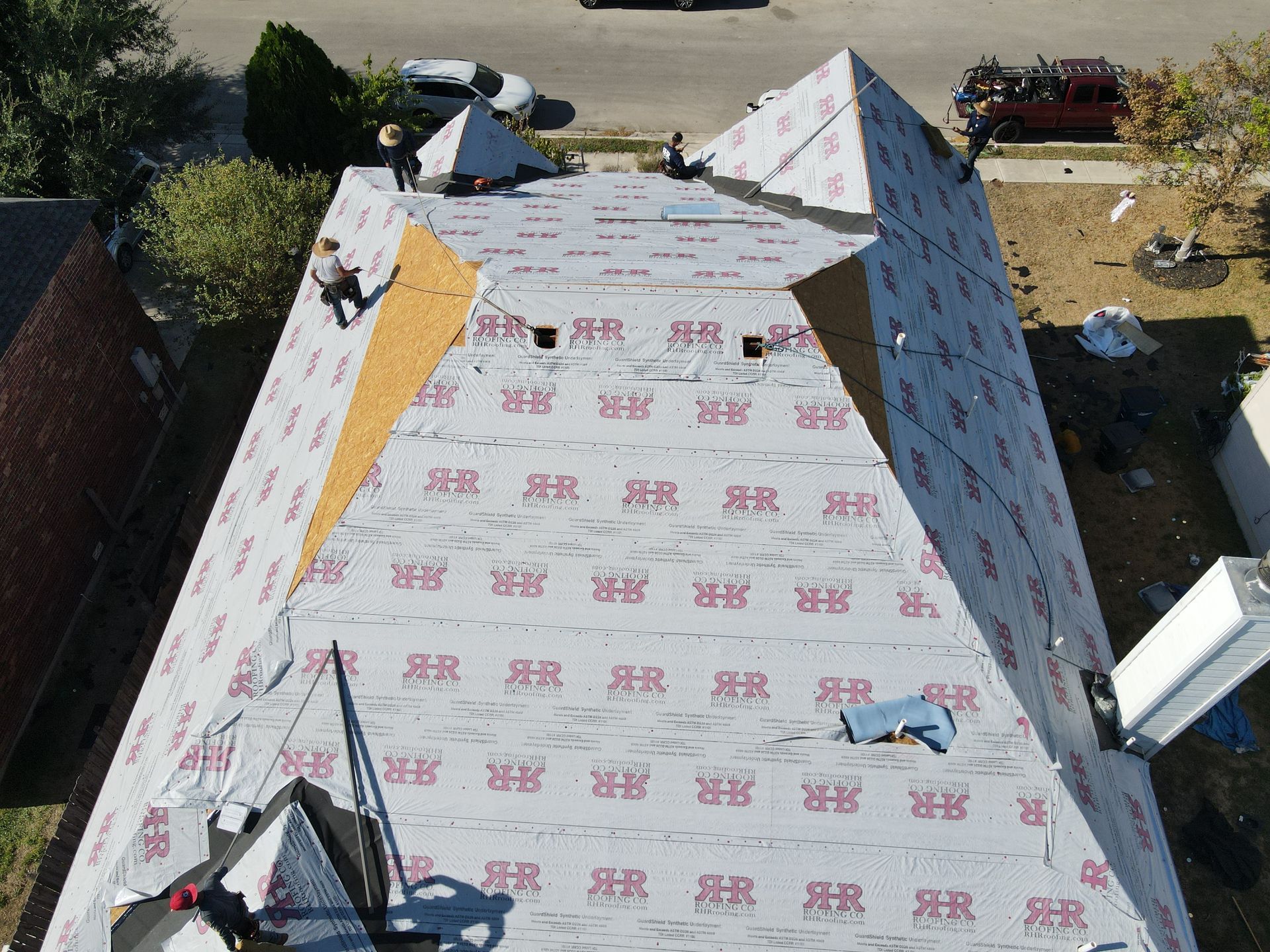 Roofers working on a house roof, laying down underlayment.