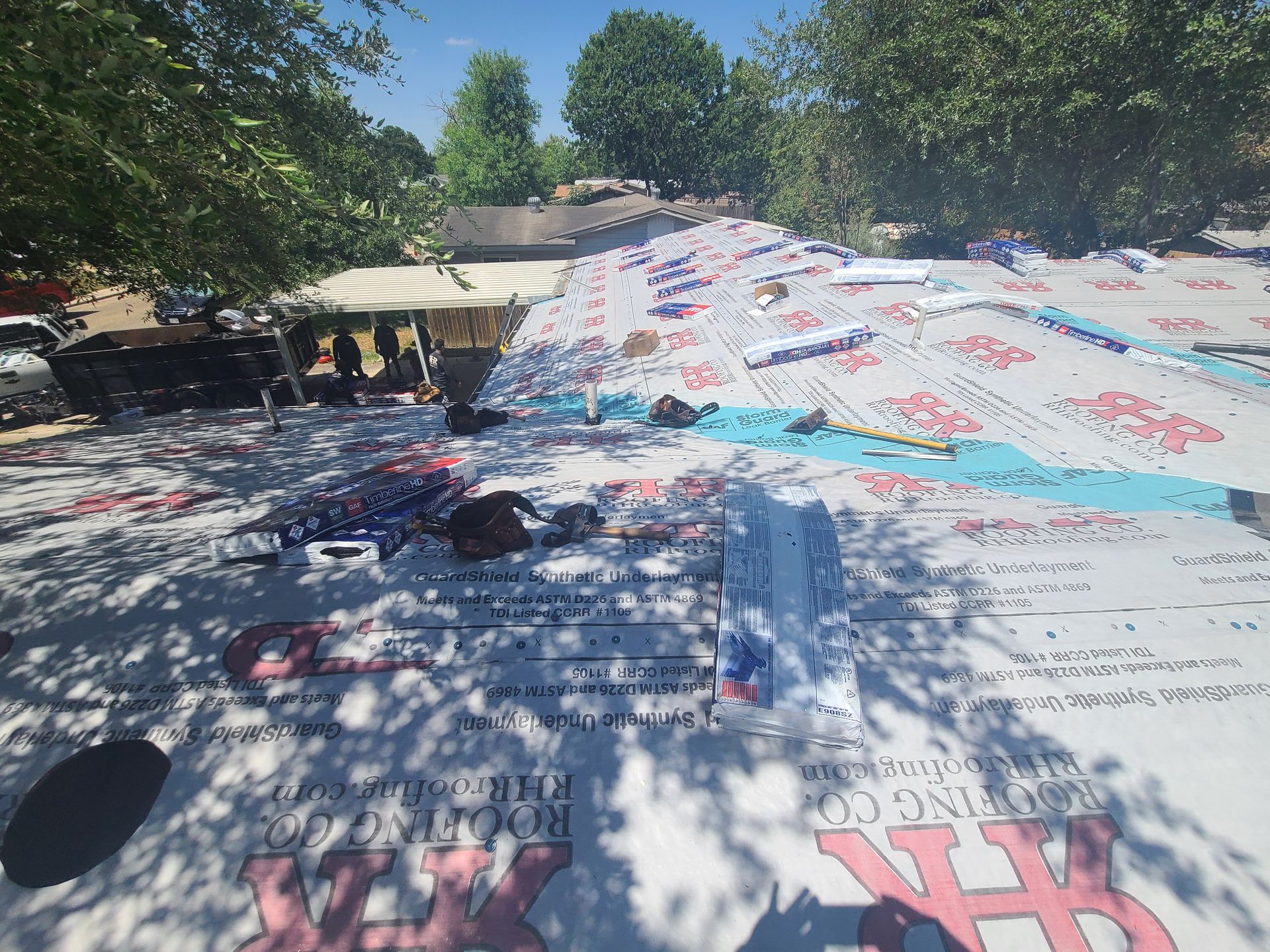 Roof with partially installed underlayment; trees in background.