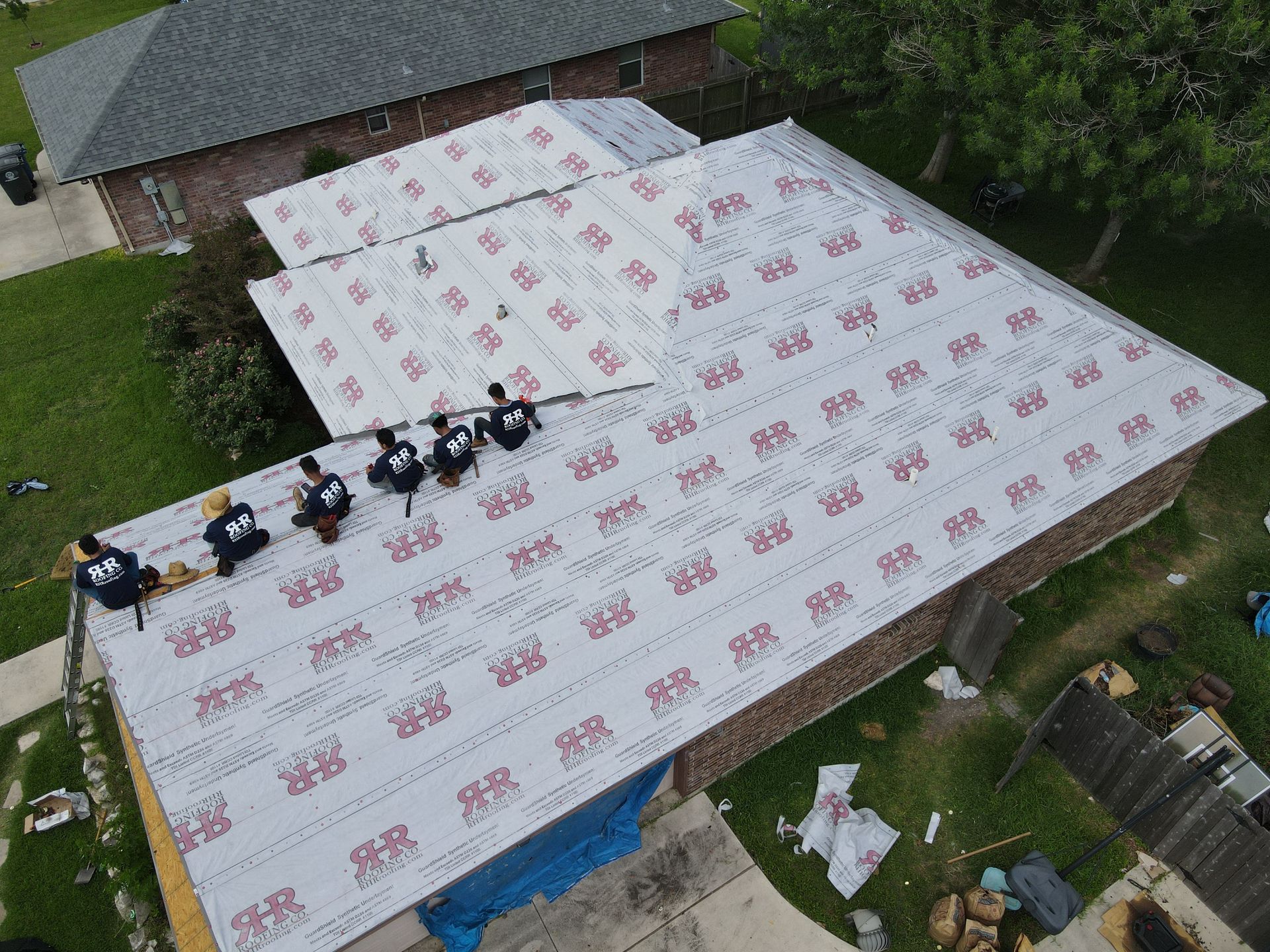 Roofers installing roofing material on a house.