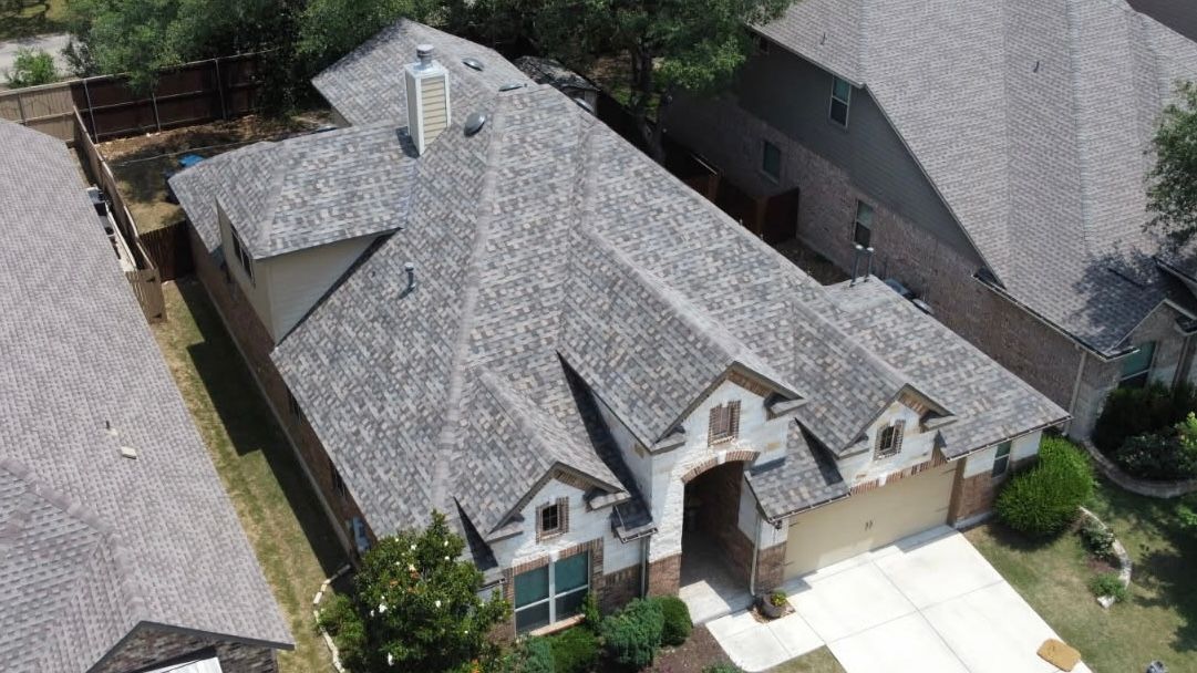 Aerial view of a single-story home with a gray roof, beige siding, and a two-car garage.