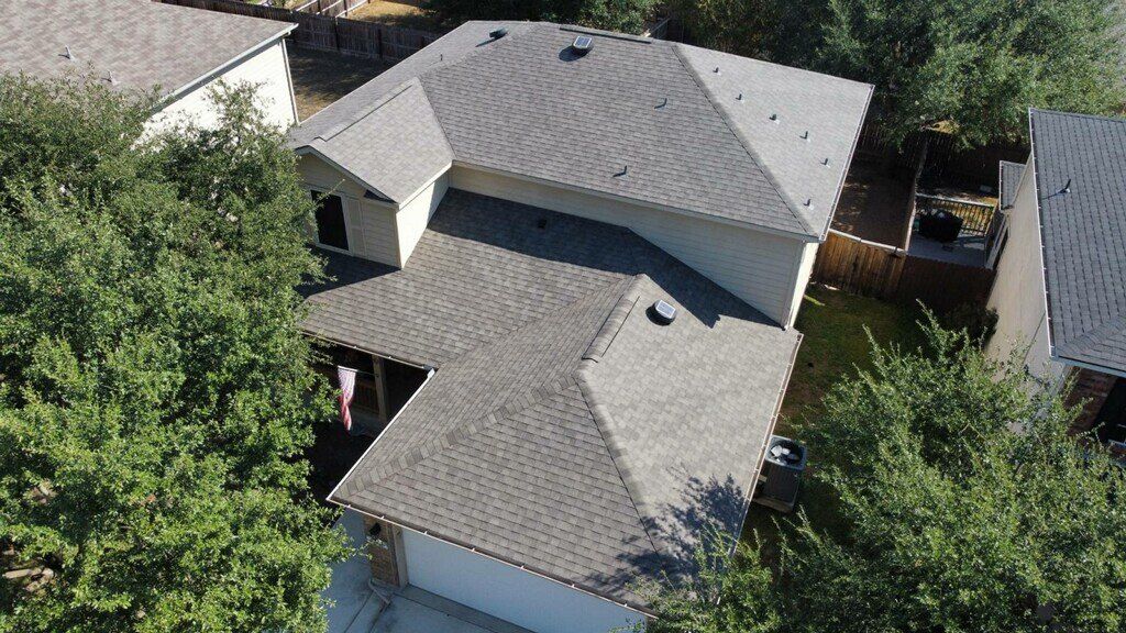 Gray-roofed house surrounded by trees. Aerial view.