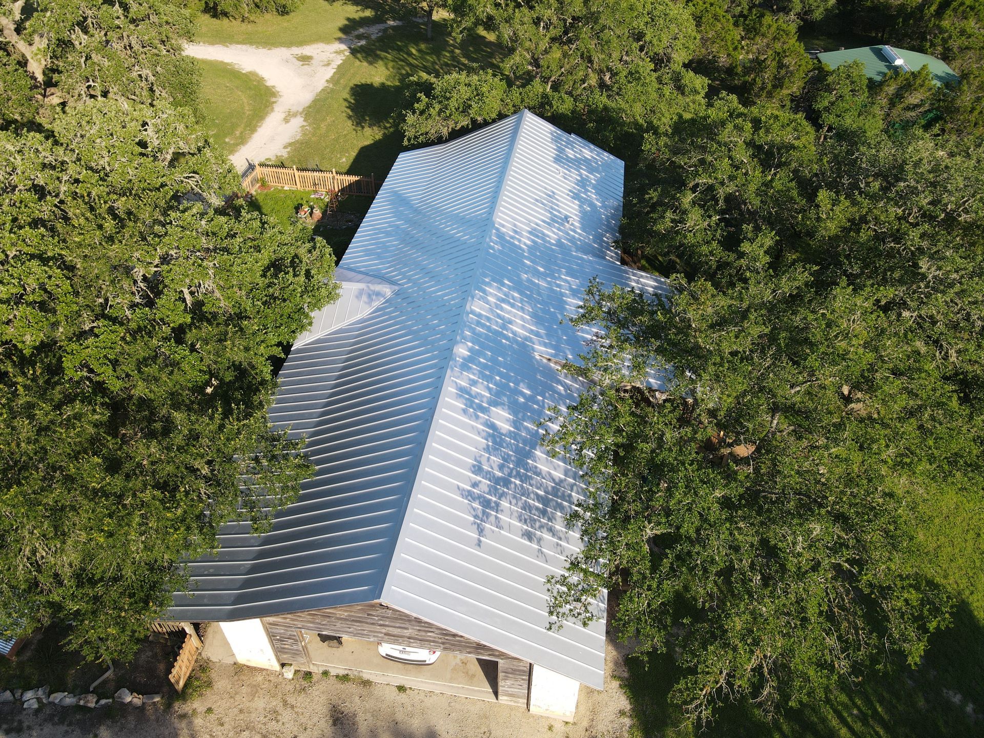 Aerial view of a metal-roofed building surrounded by trees.