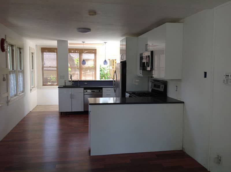 An empty kitchen with white cabinets and a black counter top.