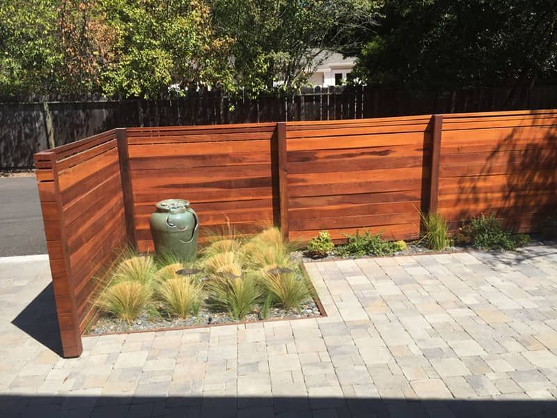 A wooden fence with a green vase in the middle of it