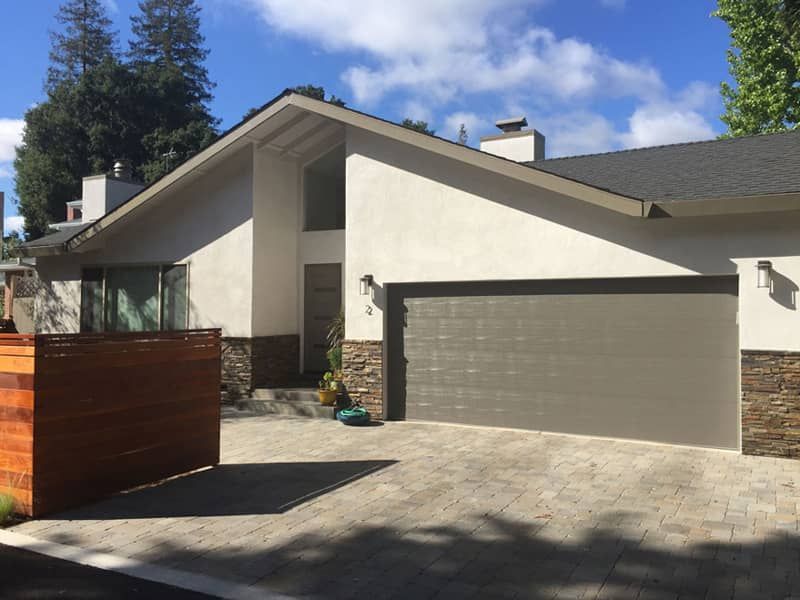 A house with two garage doors and a wooden fence