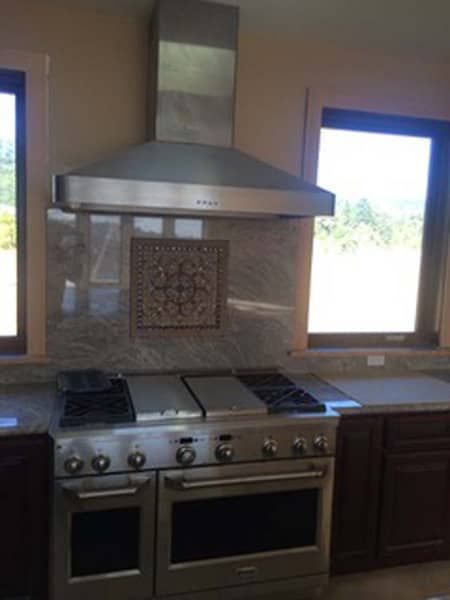 A kitchen with a stove top oven and a hood