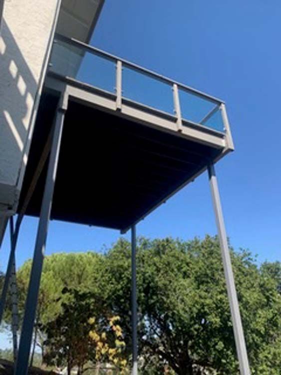 A balcony on the side of a house with trees in the background