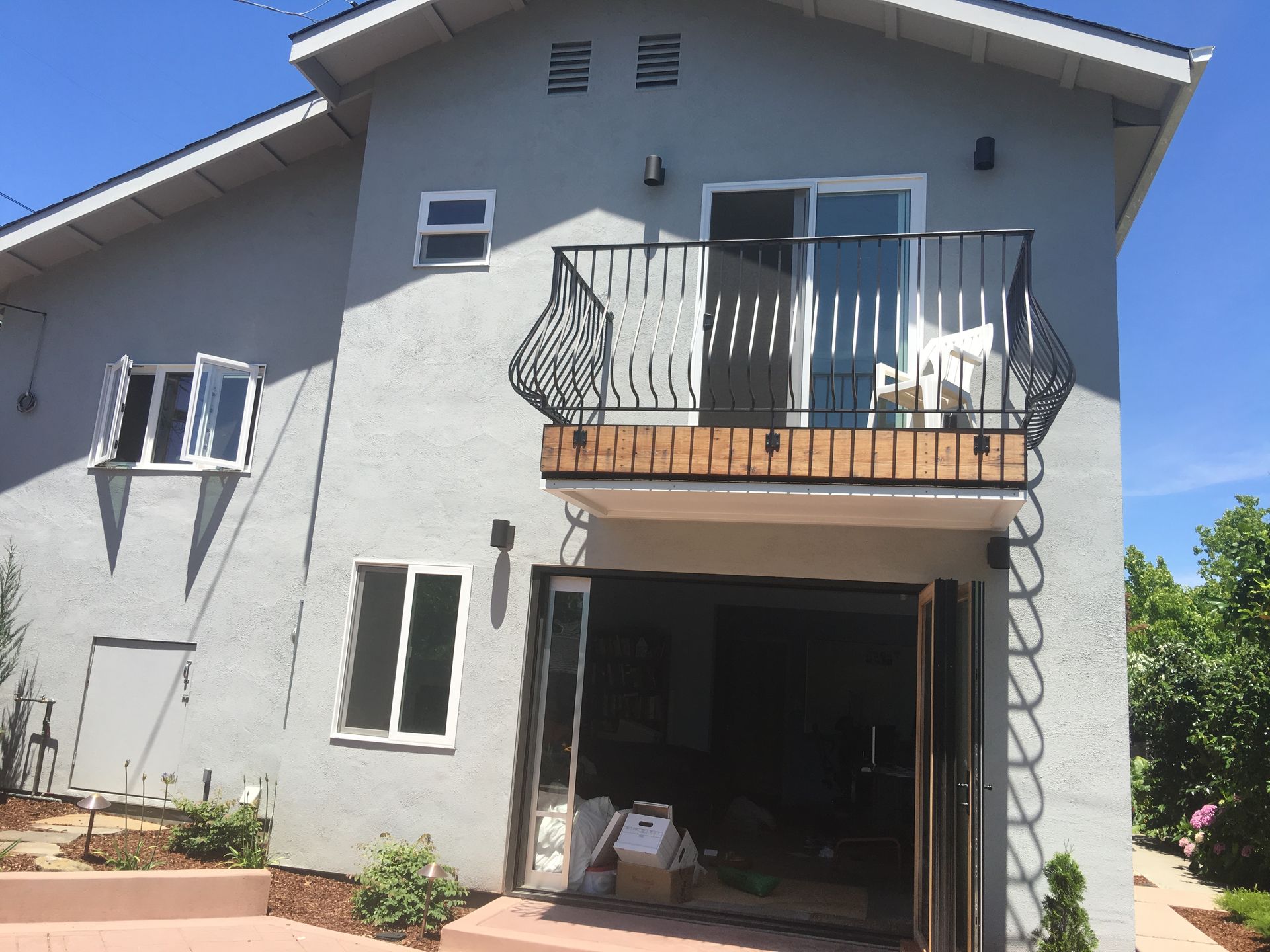 A large grey house with a balcony and stairs