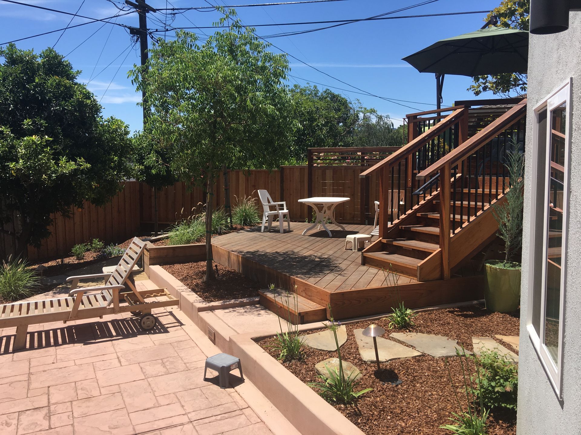 A backyard with a wooden deck and stairs