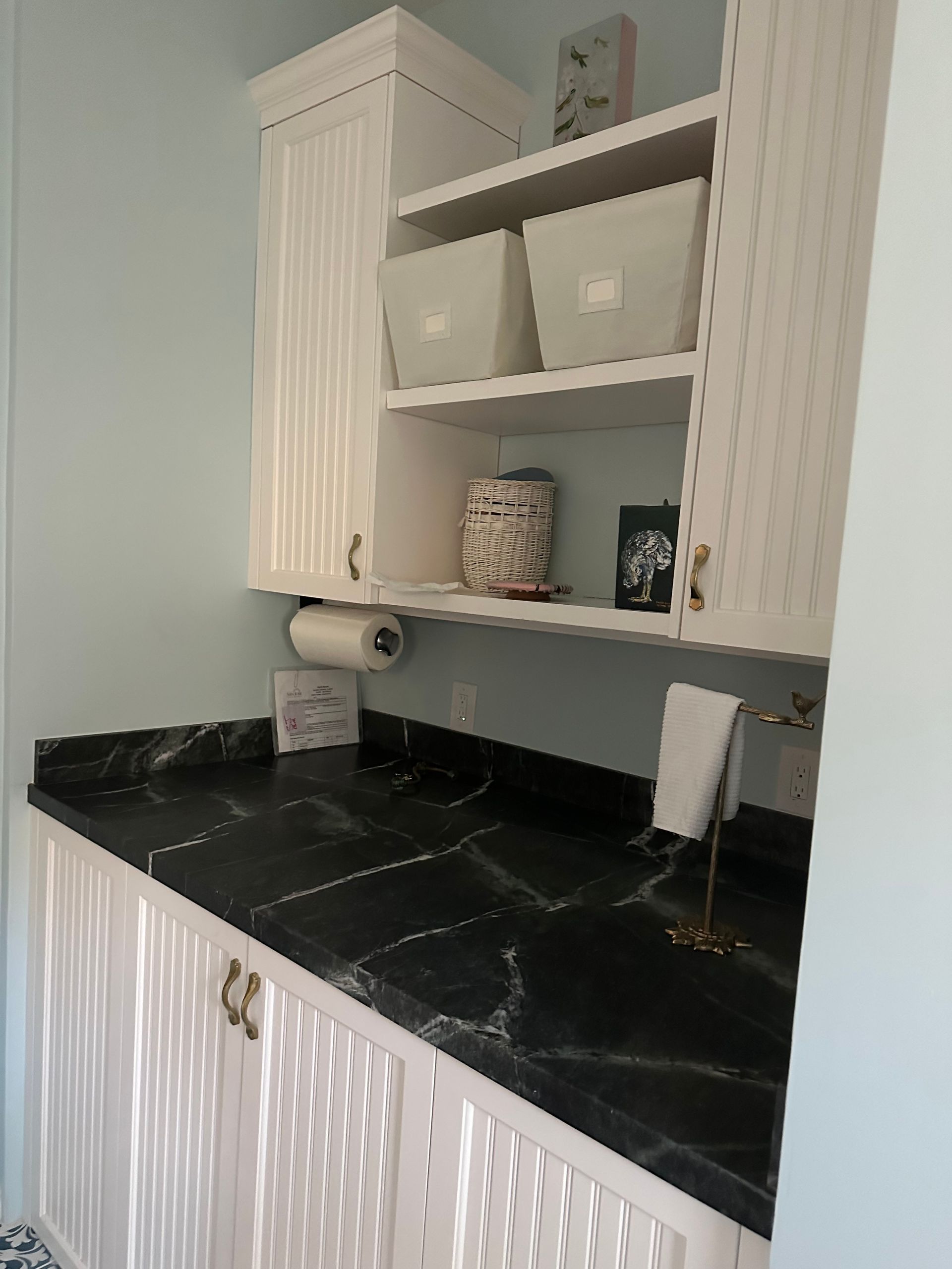 A kitchen with white cabinets and black counter tops