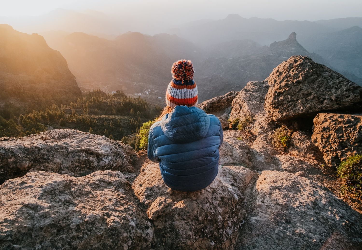 A person is sitting on top of a rocky mountain.