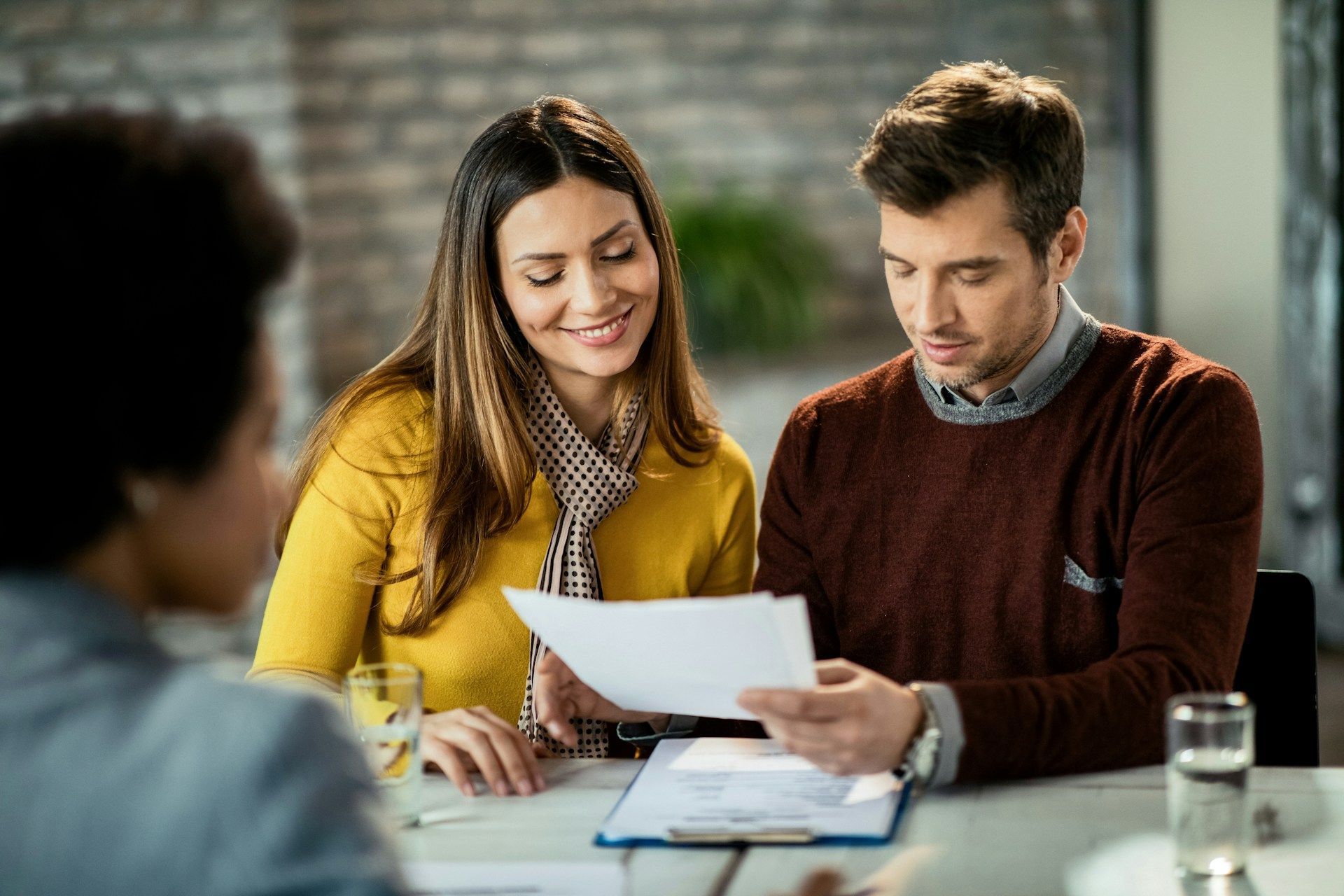 A man and a woman are sitting at a table looking at a piece of paper.