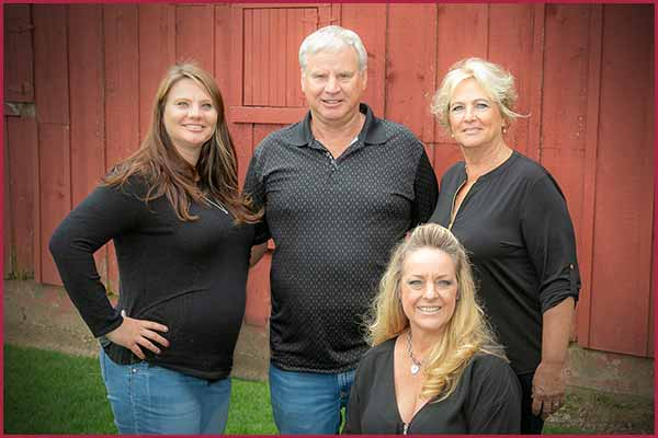 A group of people are posing for a picture in front of a red barn.