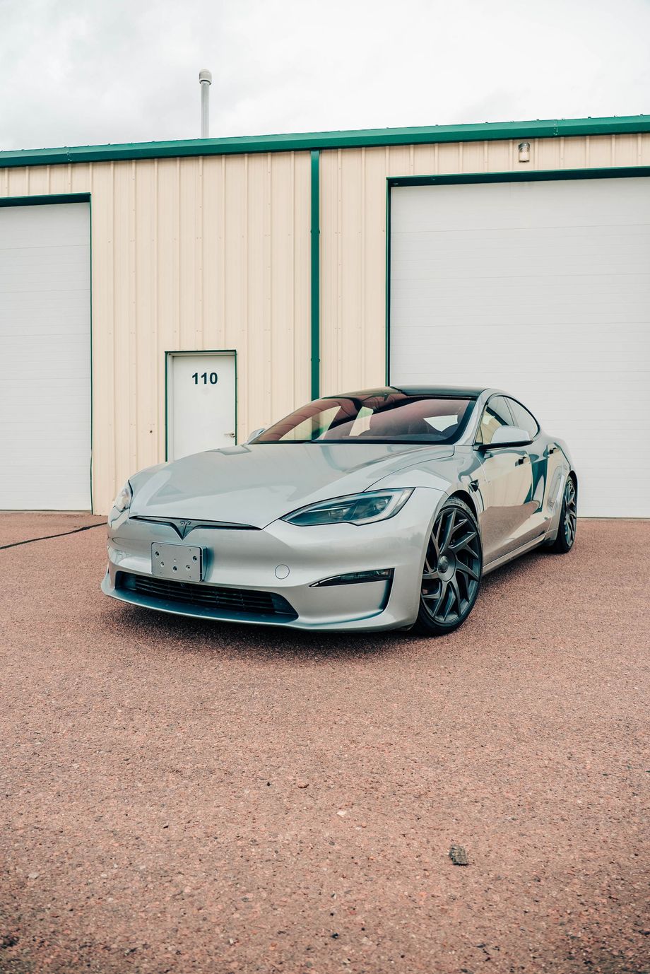 Silver sports sedan parked in front of a beige garage building