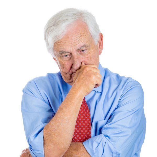Älterer Mann mit schlechten haltenden Prothesen ist frustriert