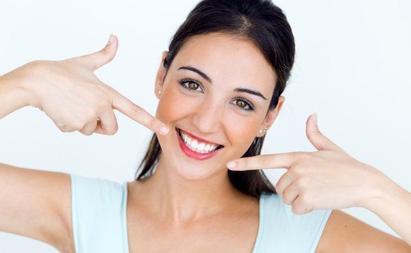 junge Frau zeigt auf ihre perfekten, weißen Zähne