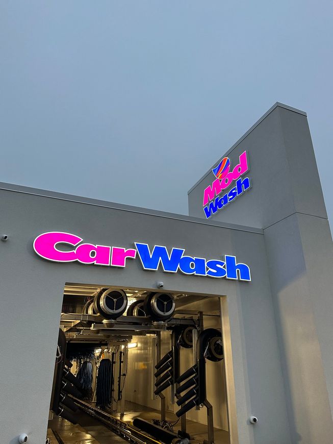A drive-through car wash facility with a pink and blue illuminated 