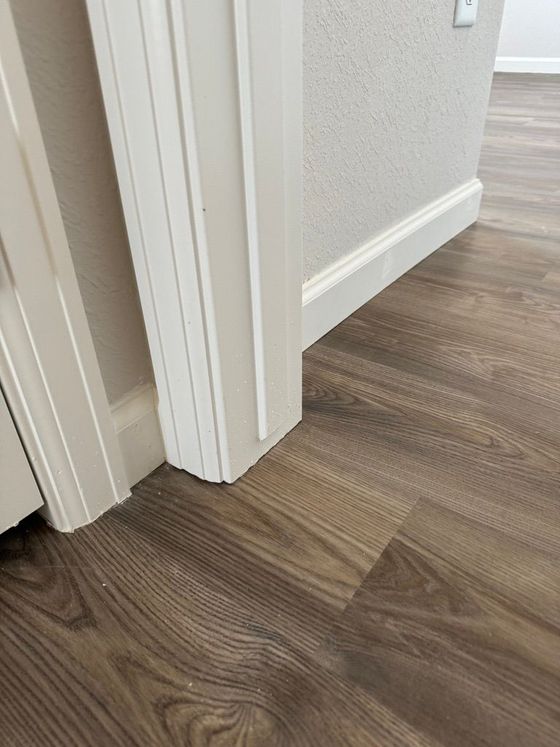 A close up of a wooden floor next to a door in a room.